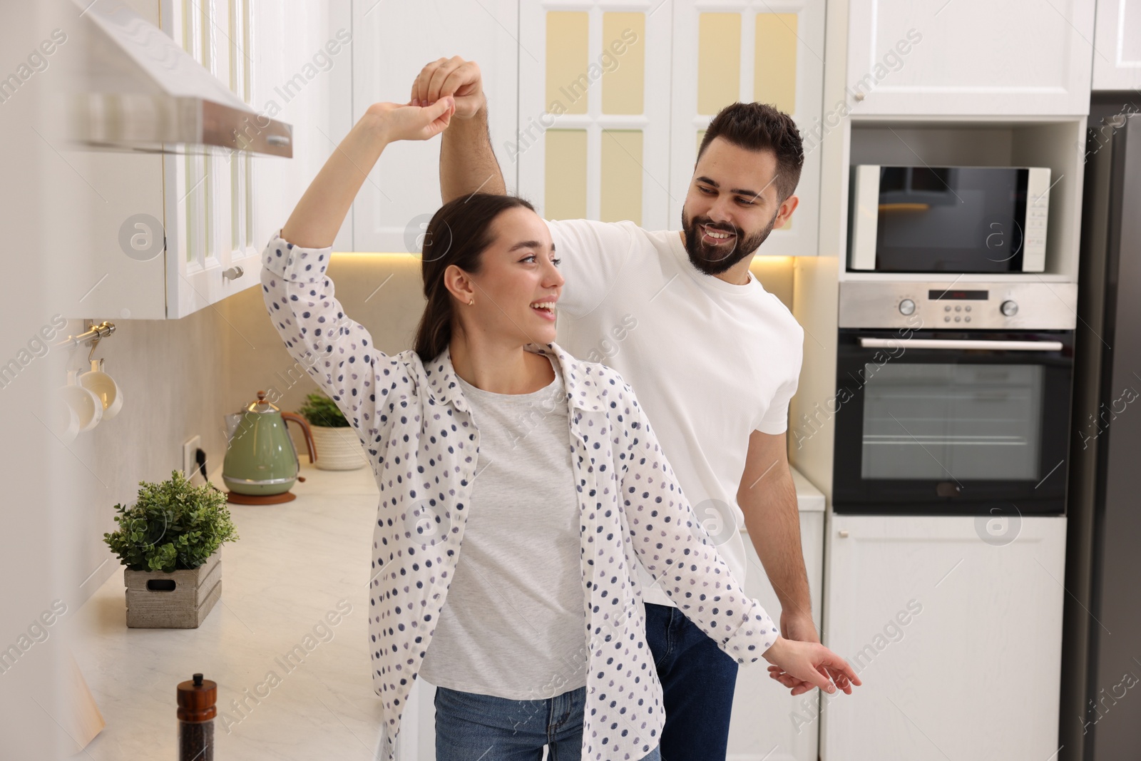 Photo of Happy lovely couple dancing together in kitchen