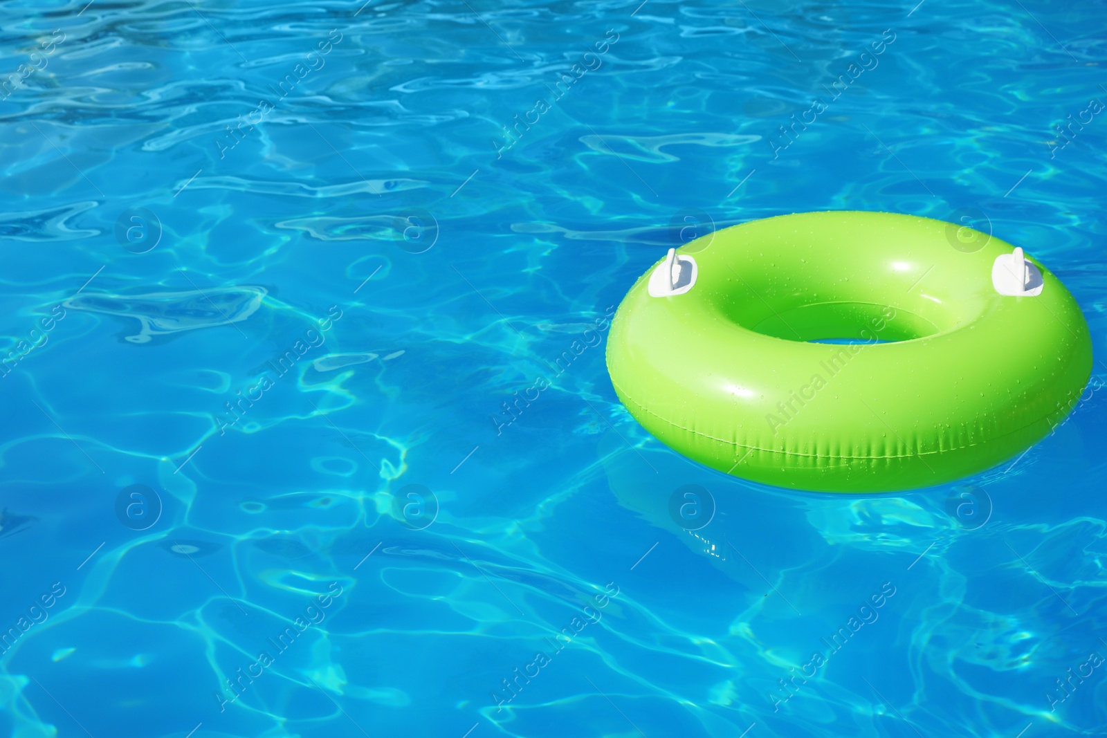 Photo of Inflatable ring floating in swimming pool on sunny day. Space for text