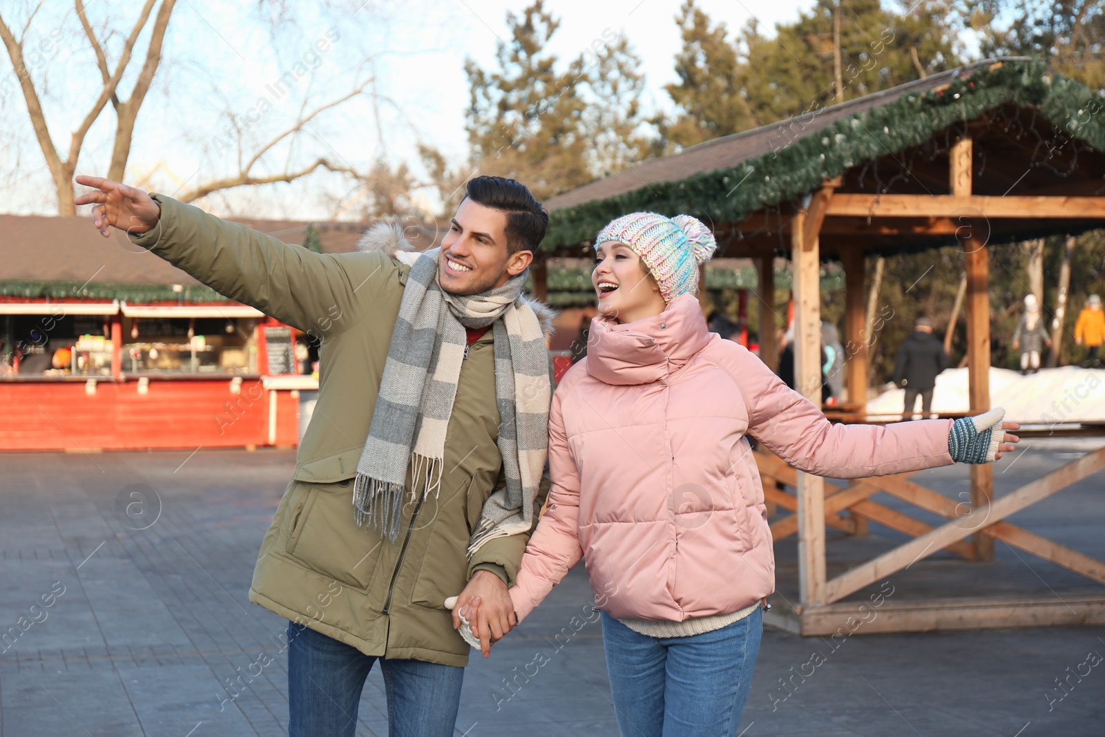 Photo of Happy couple holding hands at winter fair. Christmas celebration