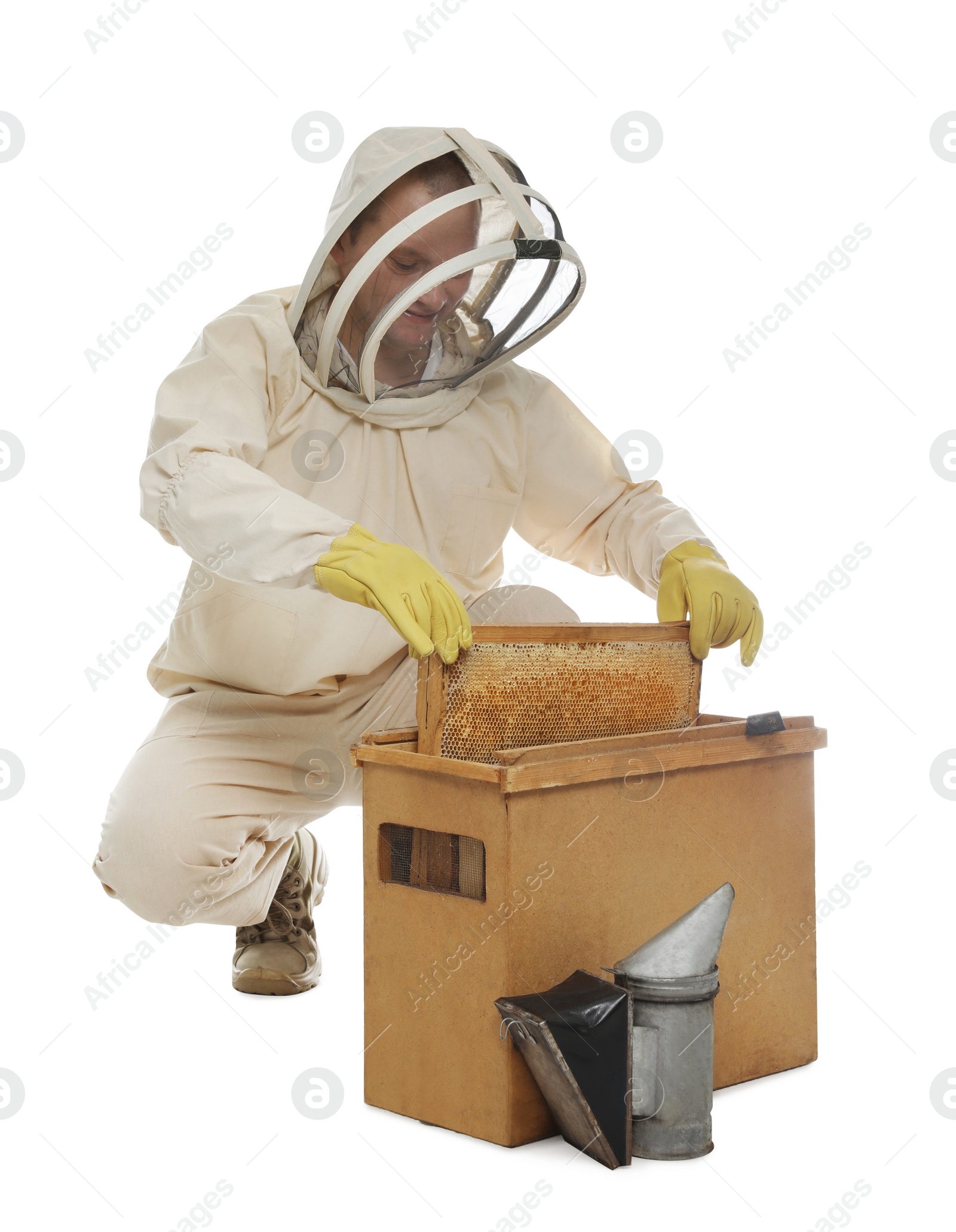 Photo of Beekeeper in uniform taking frame with honeycomb out of wooden hive on white background