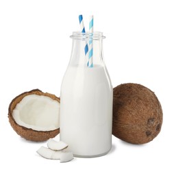 Glass bottle of delicious vegan milk and coconuts on white background