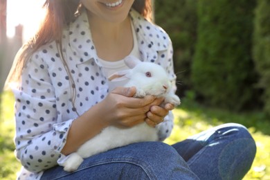 Happy woman with cute rabbit on green grass outdoors, closeup