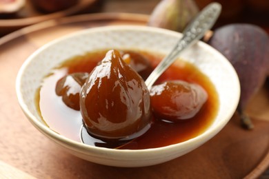 Photo of Bowl of tasty sweet fig jam on wooden table, closeup