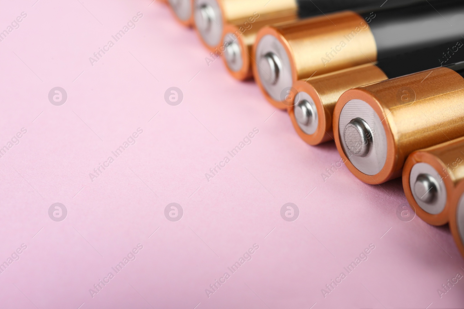 Photo of New AA batteries on pink background, closeup. Space for text