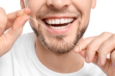 Young man flossing his teeth on white background