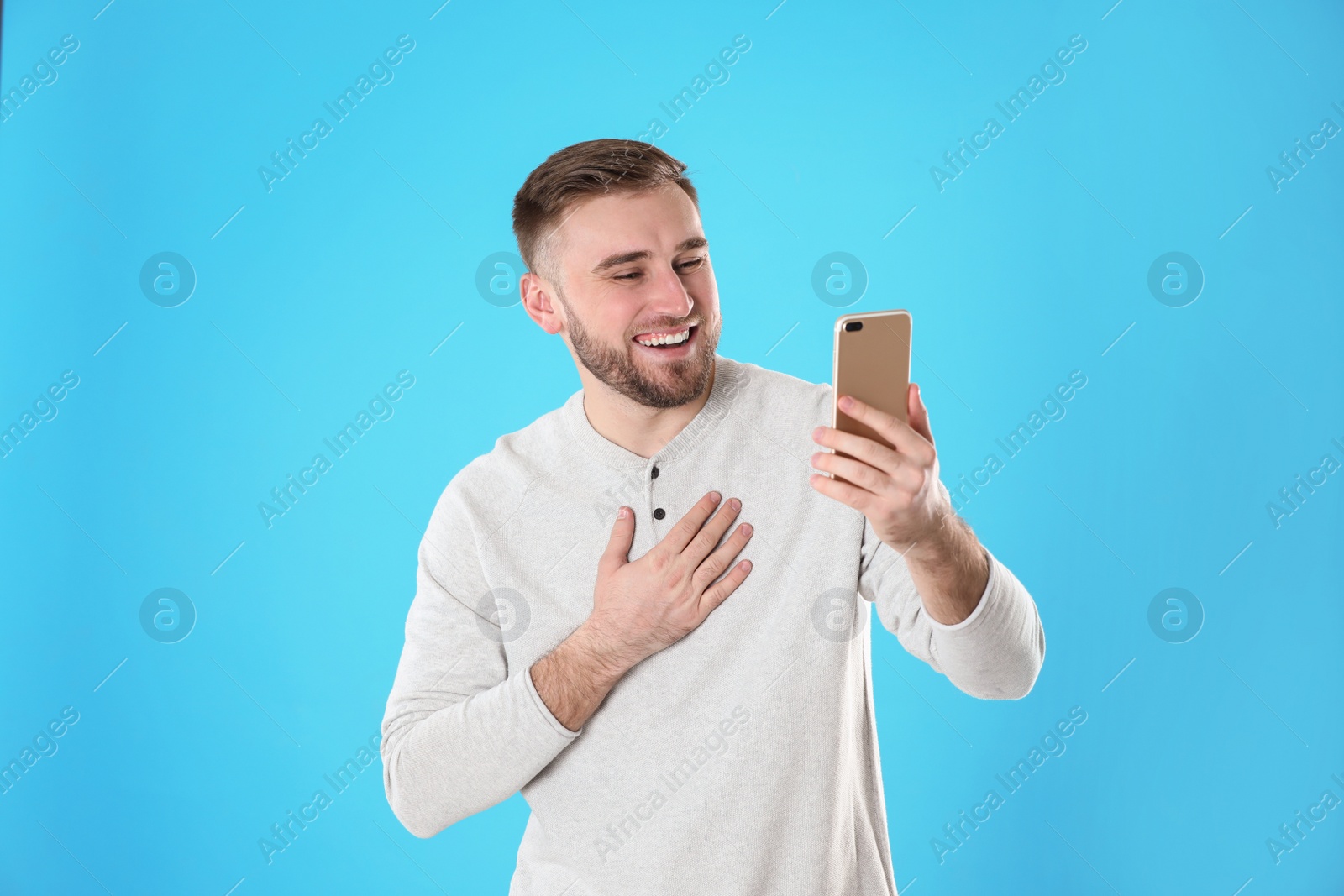 Photo of Young man using video chat on smartphone against color background