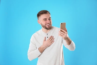 Young man using video chat on smartphone against color background