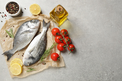 Flat lay composition with raw dorada fish on light grey table, space for text
