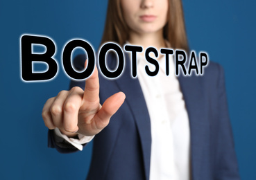 Image of Businesswoman touching virtual screen with word BOOTSTRAP against blue background, focus on hand