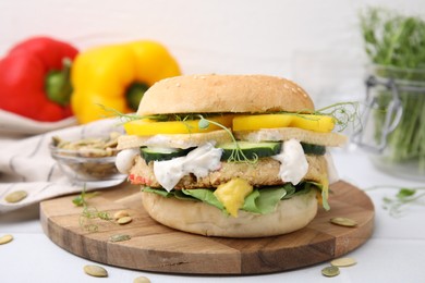 Photo of Tasty vegan burger with vegetables, sauce and patty on white table, closeup