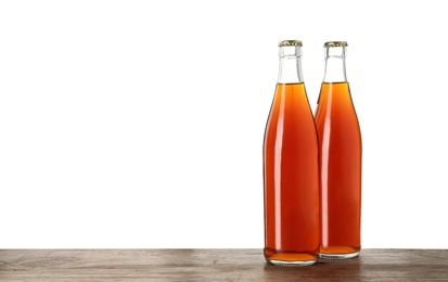 Photo of Bottles of delicious kvass on wooden table against white background