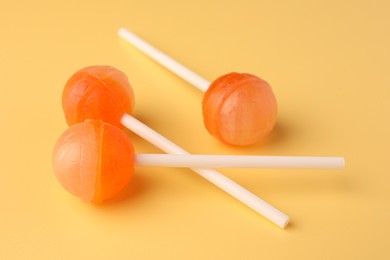 Photo of Three tasty lollipops on yellow background, closeup