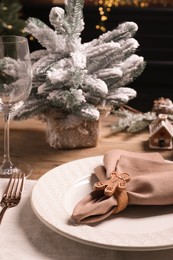 Photo of Plate, fork and fabric napkin with beautiful decorative ring on wooden table