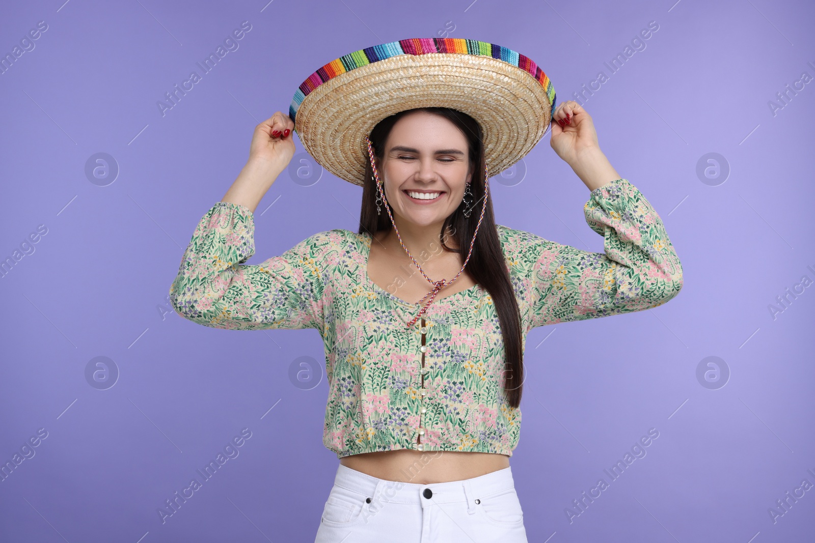 Photo of Young woman in Mexican sombrero hat on violet background