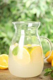 Photo of Cool freshly made lemonade in glass pitcher on wooden table