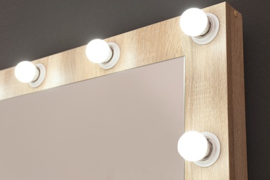 Photo of Mirror with light bulbs on grey wall, closeup. Dressing room