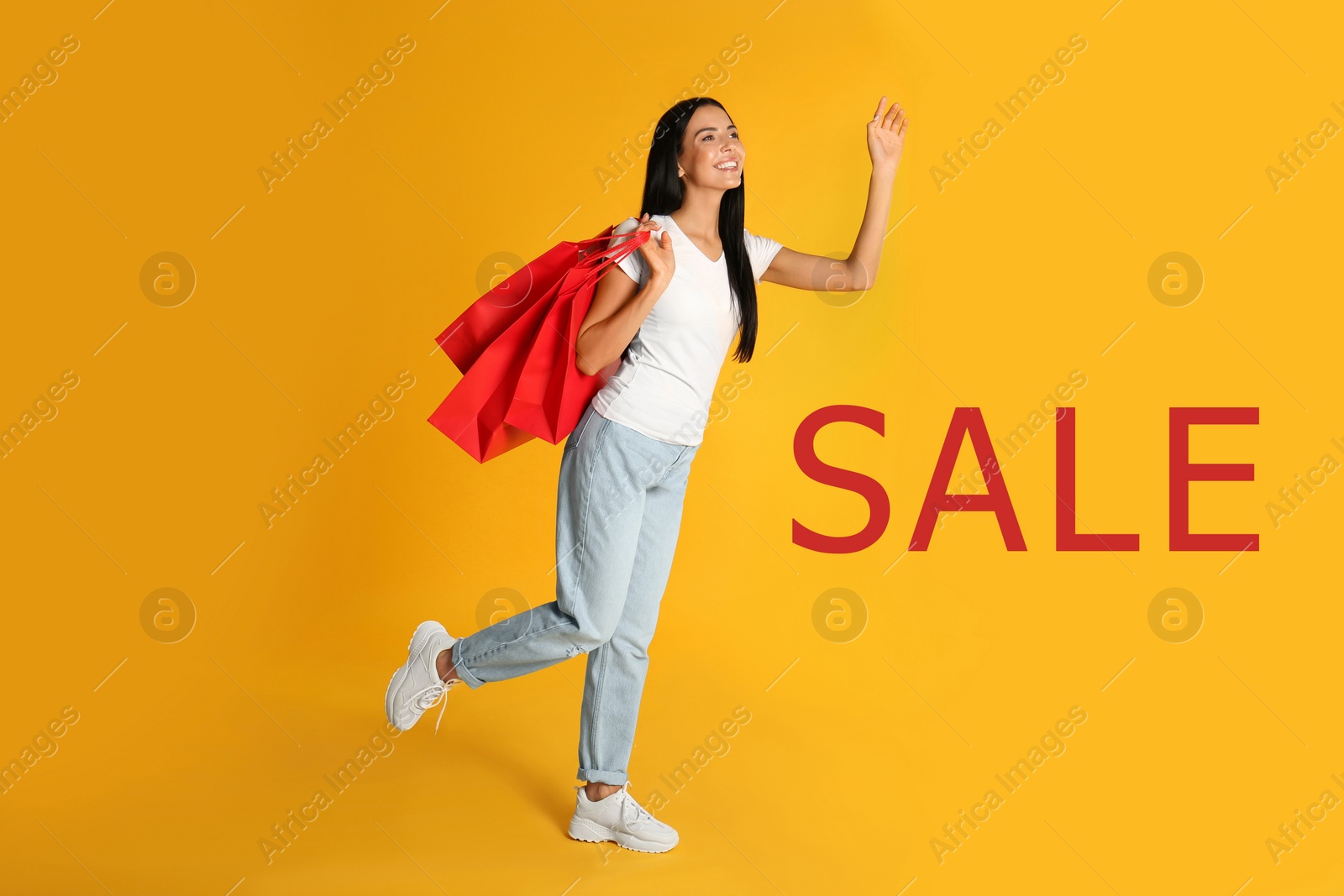 Image of Beautiful young woman with paper shopping bags and word SALE on yellow background