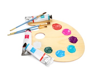 Photo of Wooden artist's palette with brushes and paints on white background