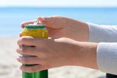 Photo of Woman opening can with sparkling drink at beach, closeup