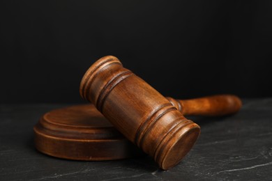 Photo of Wooden gavel on dark textured table, closeup