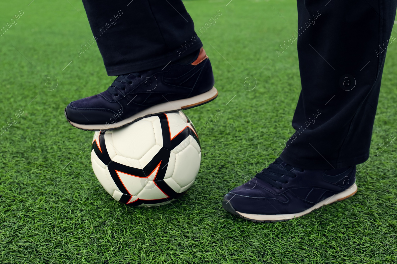 Photo of Man with soccer ball on green grass at stadium, closeup