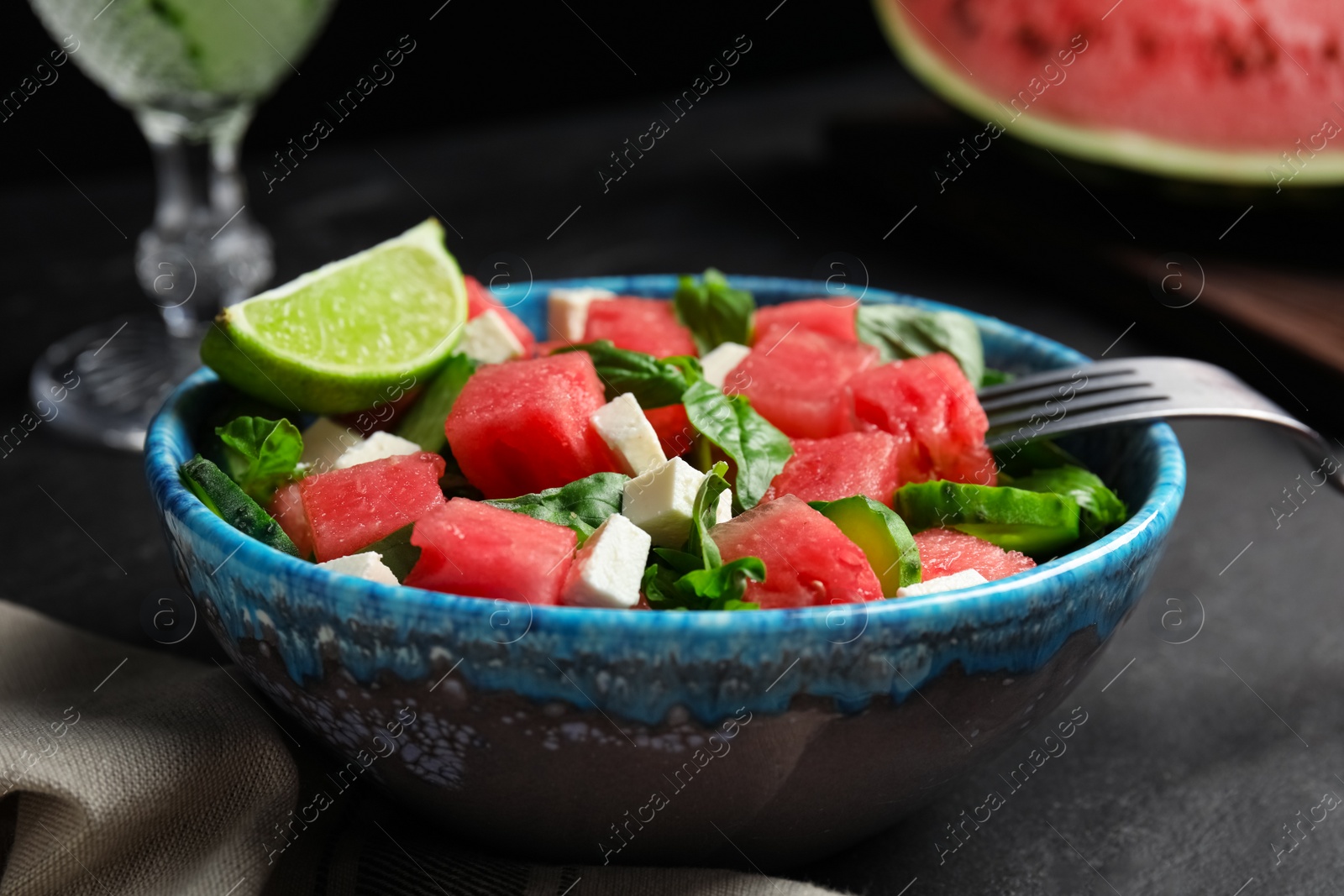 Photo of Delicious salad with watermelon served on black table, closeup