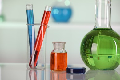 Photo of Laboratory analysis. Different glassware with liquids on white table against blurred background, closeup