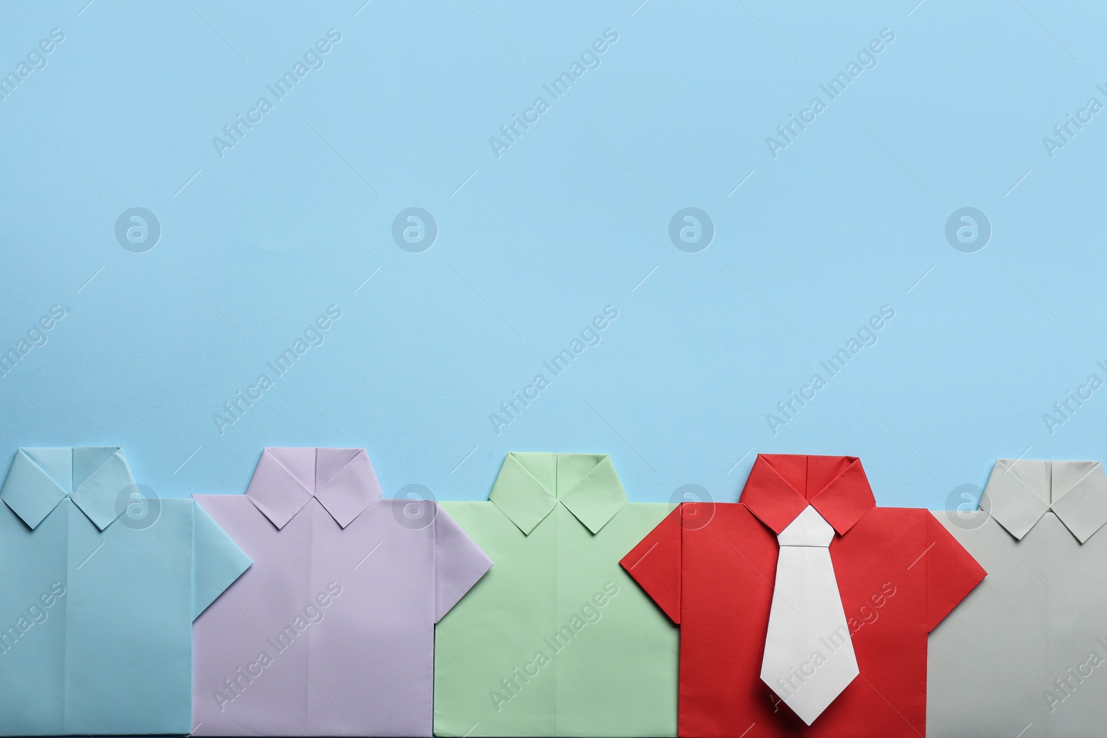 Photo of Many paper shirts on light blue background, flat lay with space for text. Recruiter searching employee