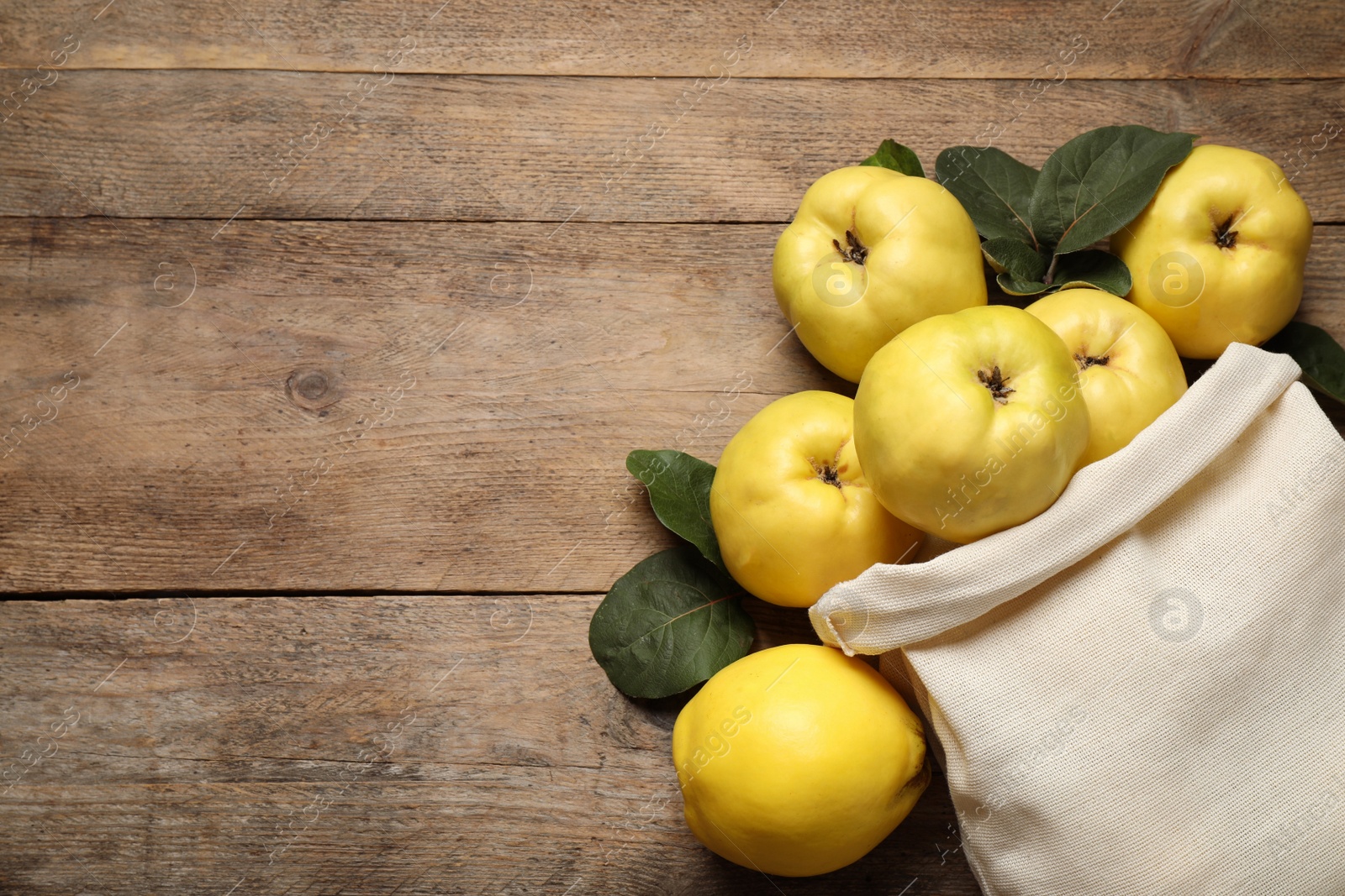 Photo of Fresh ripe organic quinces on wooden table, flat lay. Space for text