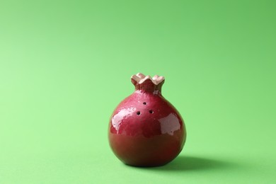Photo of Pomegranate shaped spice shaker on green background