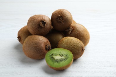 Photo of Cut and whole fresh kiwis on white wooden table