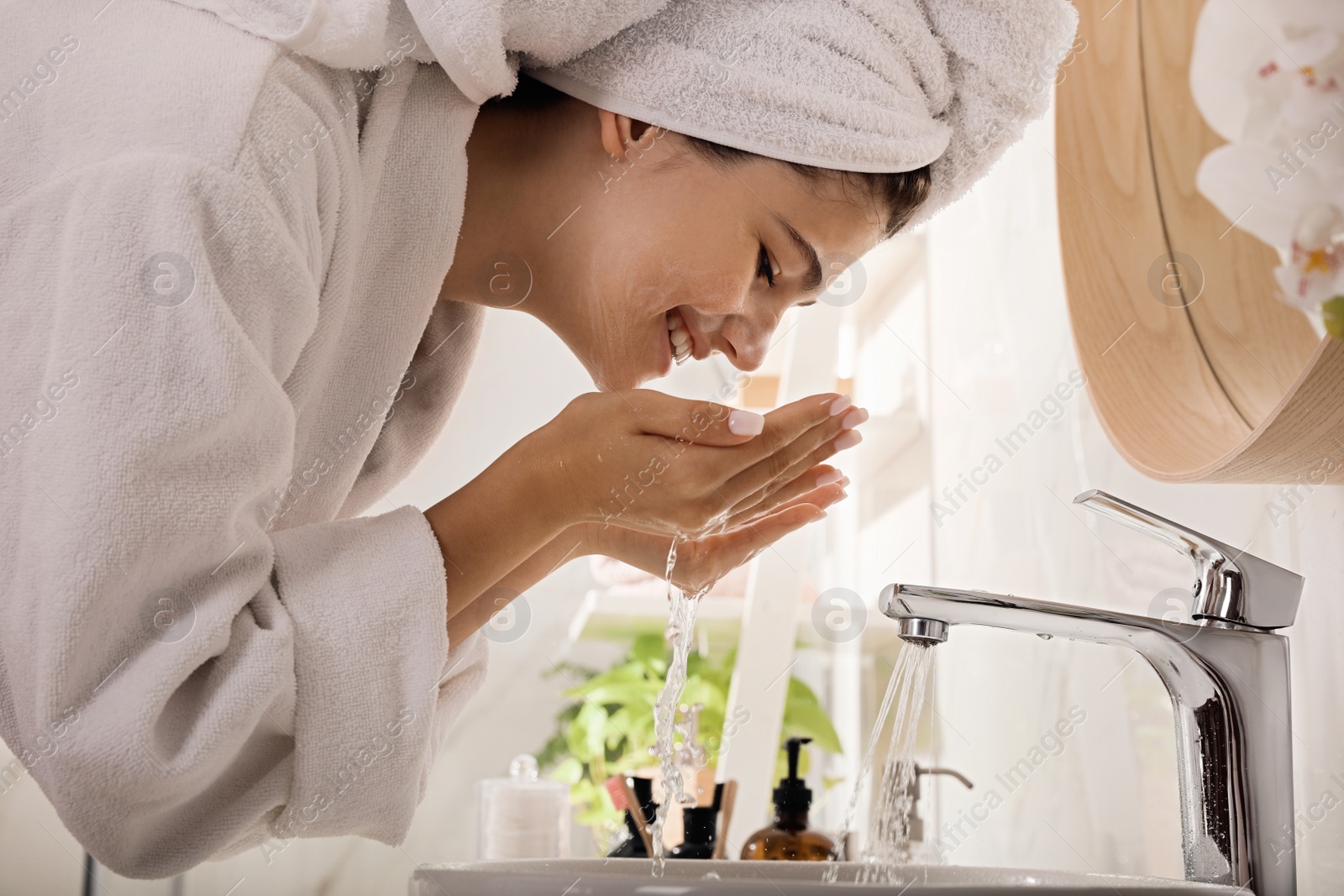 Photo of Beautiful teenage girl washing face with cleansing foam in bathroom. Skin care cosmetic