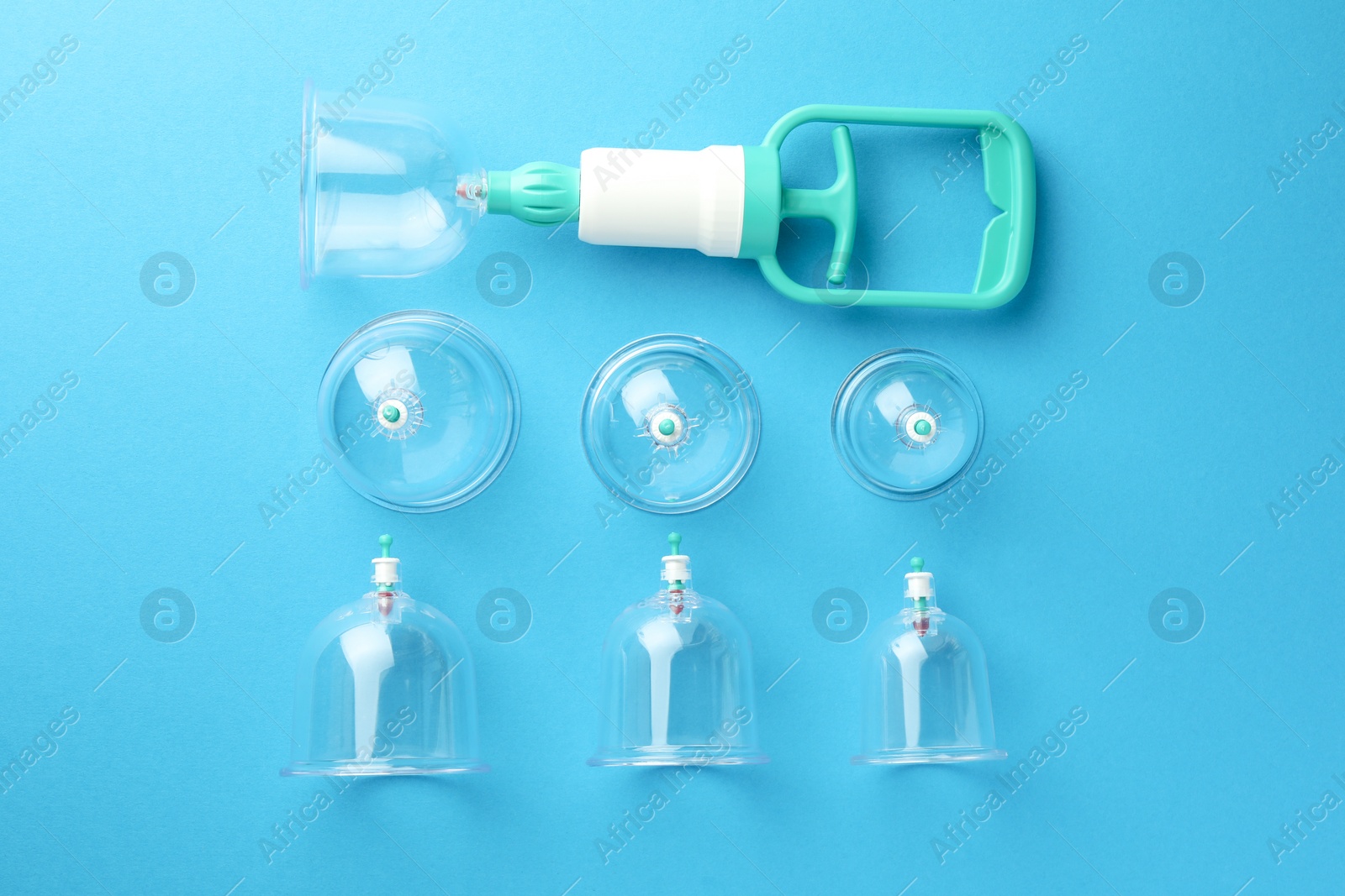 Photo of Plastic cups and hand pump on light blue background, flat lay. Cupping therapy