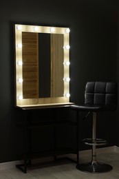 Beautiful mirror with light bulbs and chair in makeup room