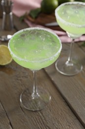 Delicious Margarita cocktail in glasses on wooden table, closeup