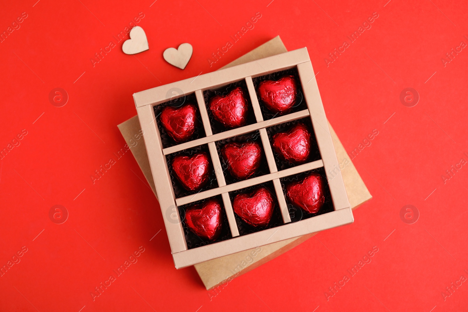 Photo of Tasty heart shaped chocolate candies on red background, flat lay. Happy Valentine's day