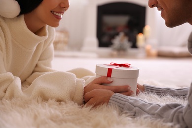 Photo of Couple holding Christmas gift box in living room, closeup