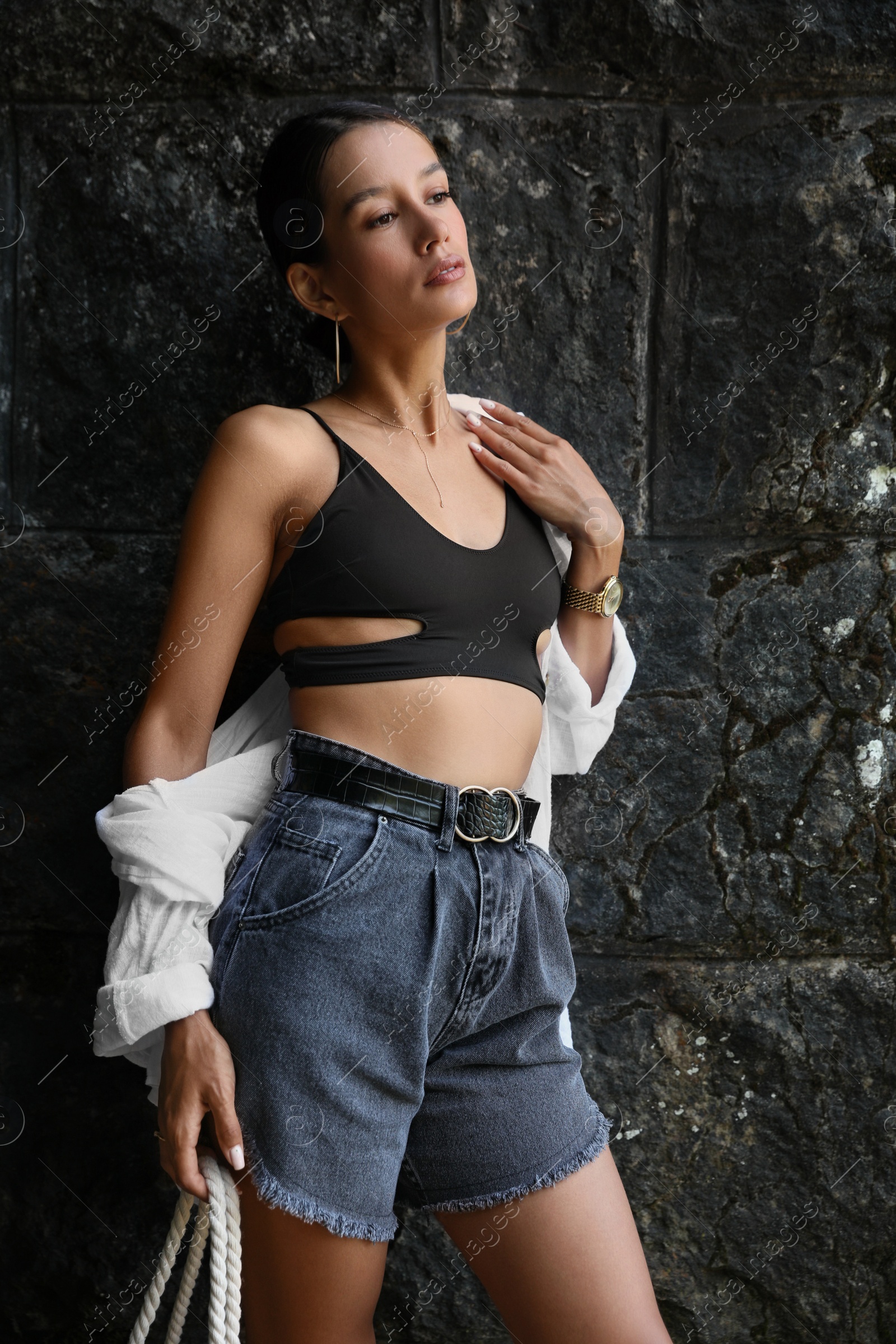 Photo of Beautiful young woman near dark stone wall