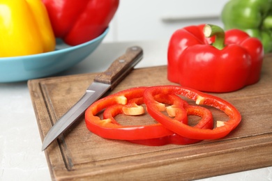 Wooden board with cut paprika pepper on table