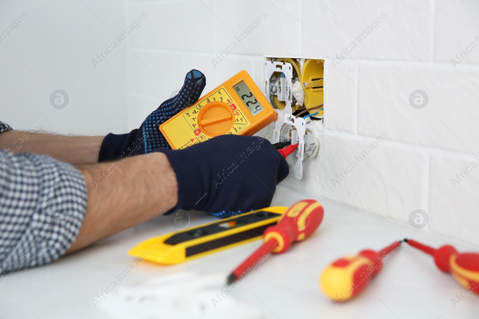 Photo of Electrician with tester checking voltage indoors, closeup