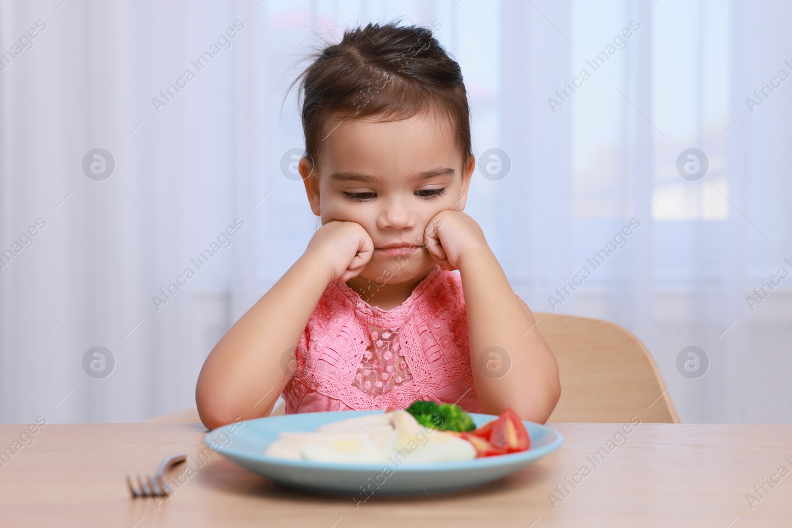 Photo of Cute little girl refusing to eat her breakfast at home