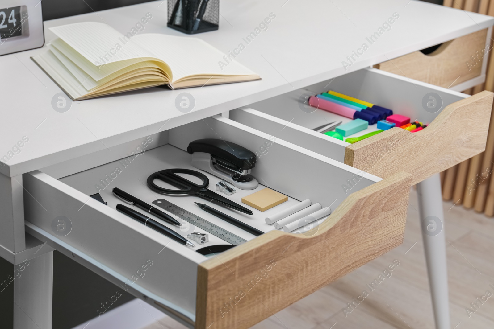 Photo of Office supplies in open desk drawers indoors