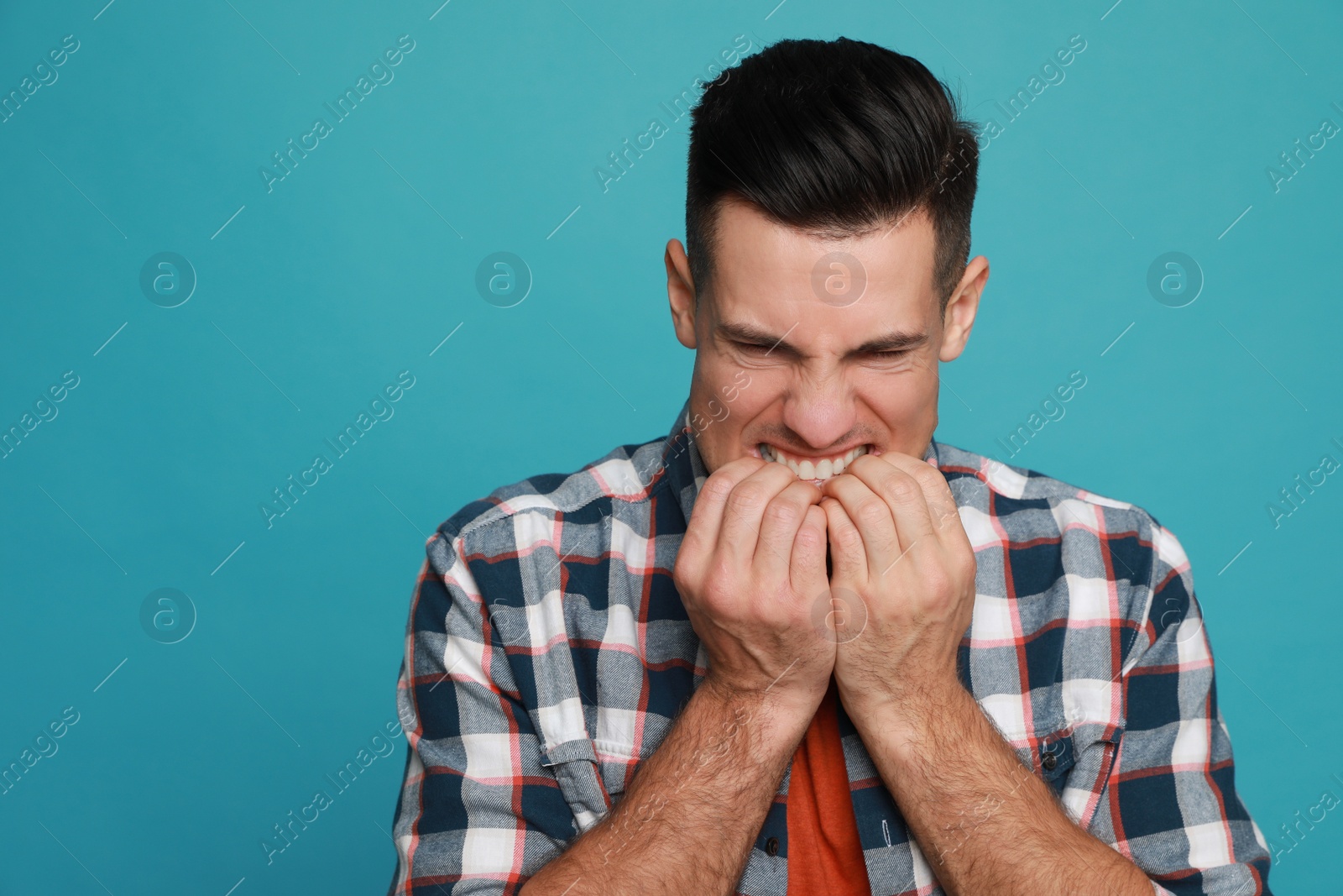 Photo of Man biting his nails on light blue background, space for text. Bad habit