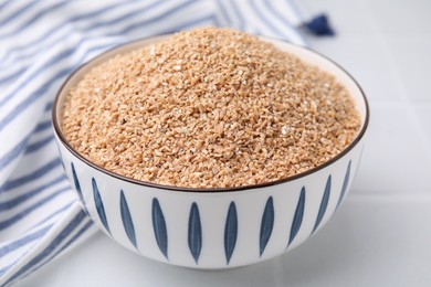 Photo of Dry wheat groats in bowl on white table, closeup