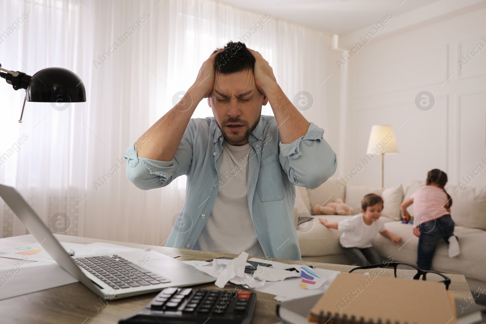 Photo of Overwhelmed man combining parenting and work at home