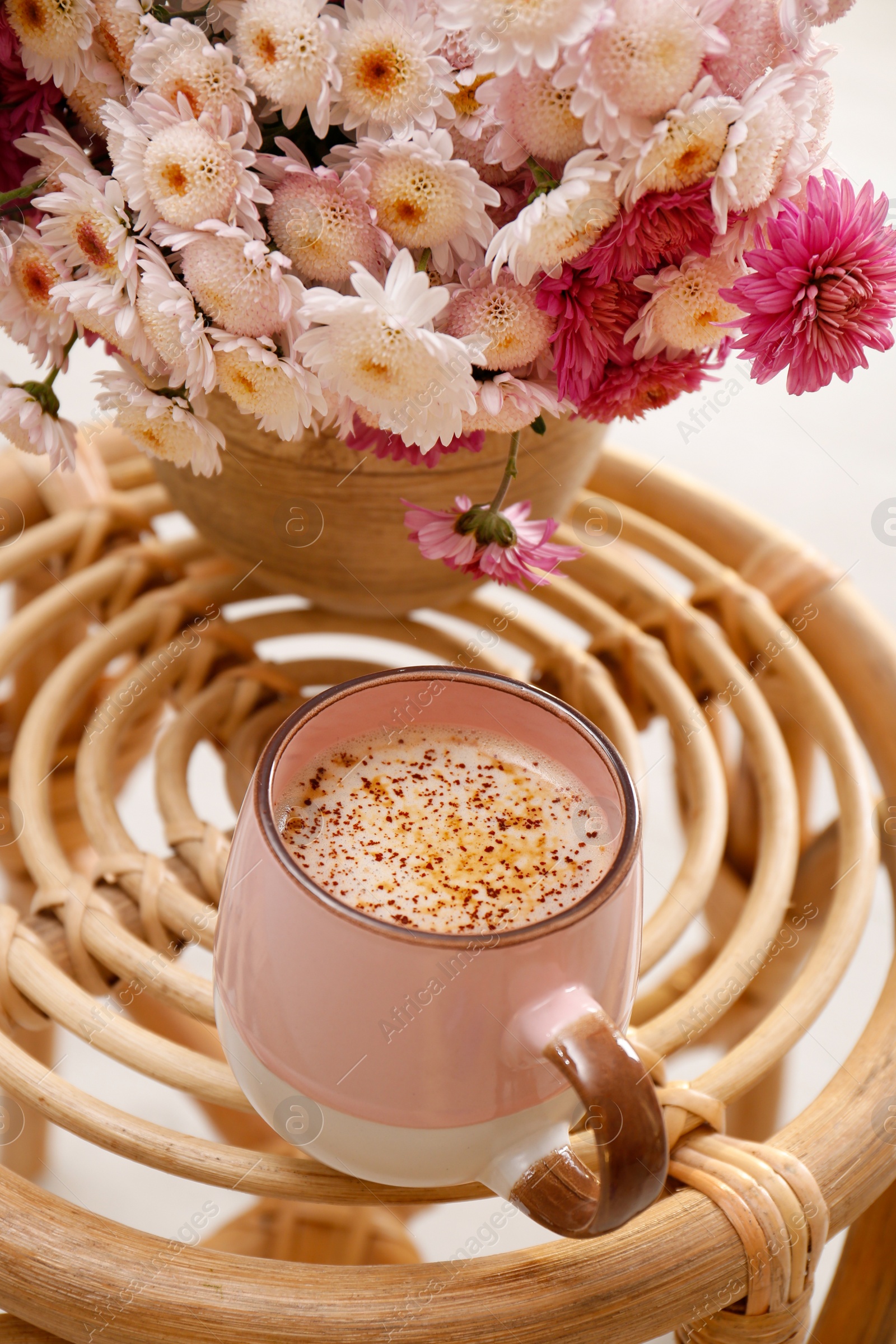 Photo of Cup of fresh coffee and beautiful bouquet on wooden stand. Good morning