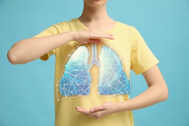 Woman holding hands near chest with illustration of lungs on turquoise background, closeup