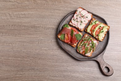 Photo of Different tasty sandwiches on wooden table, top view. Space for text