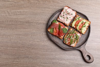 Different tasty sandwiches on wooden table, top view. Space for text