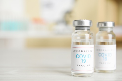 Photo of Vials with vaccine against Covid-19 on white table indoors. Space for text